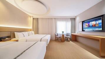A hotel room with two beds, a desk, a TV, and a window with curtains.