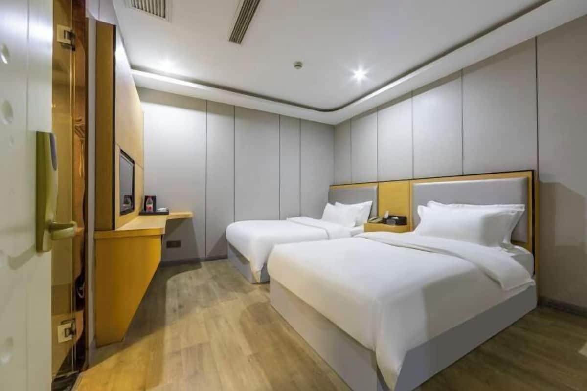 A hotel room with two beds, a wooden desk, and a mirror.