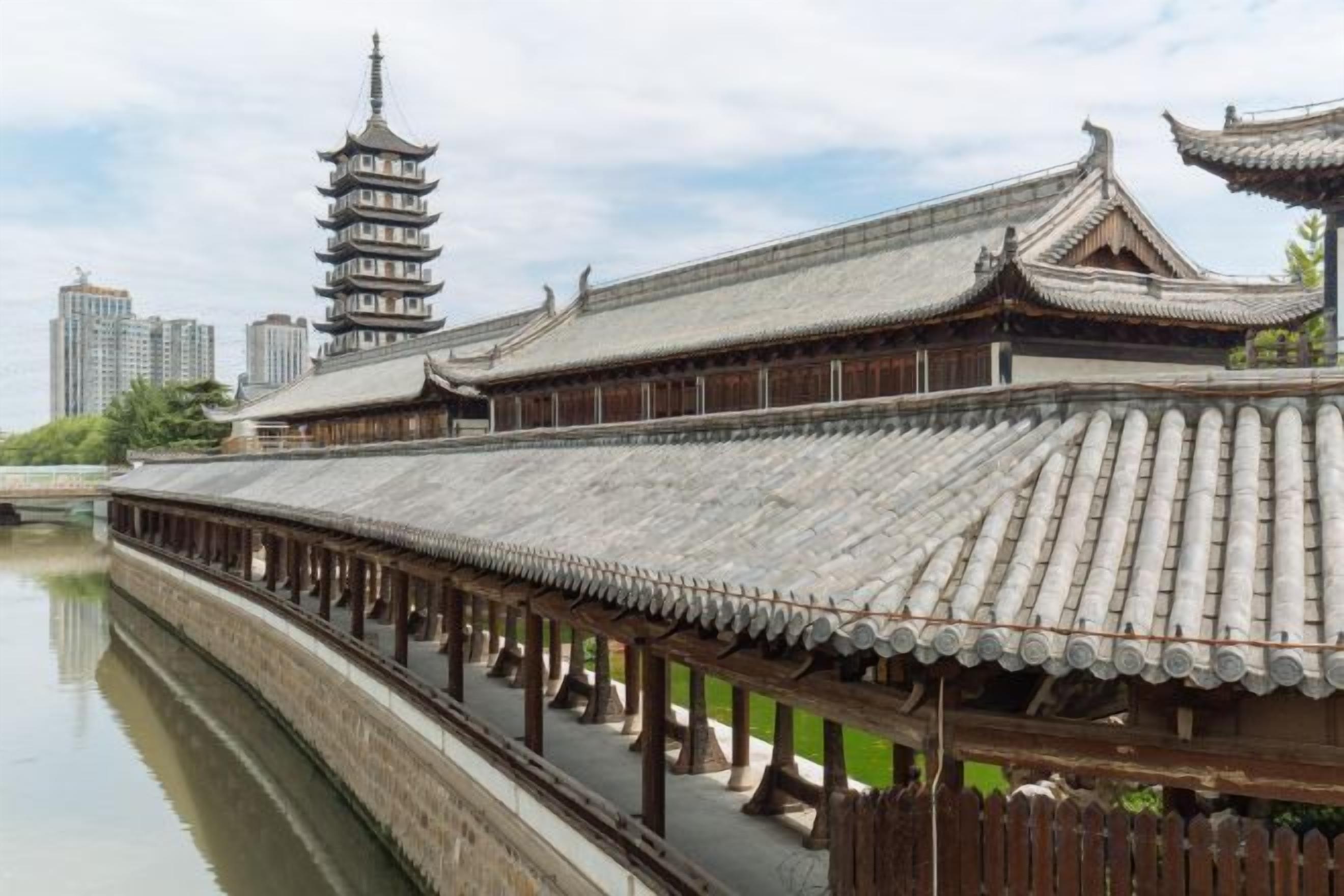 Un edificio tradicional con techo de tejas y una estructura parecida a una pagoda al fondo.