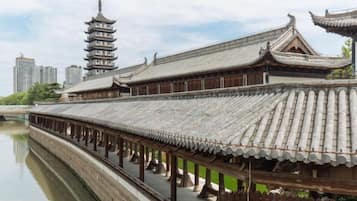 Un edificio tradicional con techo de tejas y una estructura parecida a una pagoda al fondo.