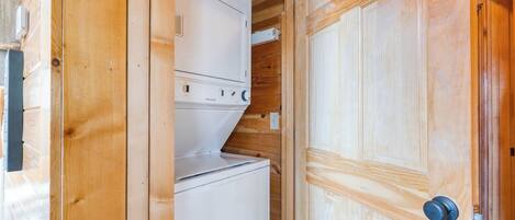 A wooden interior with a white appliance, likely a washer and dryer, and a wooden door with a round handle.