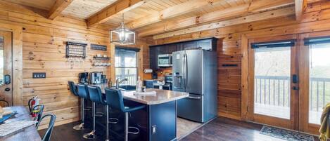 A wooden cabin interior with a kitchen, dining area, and bar seating.