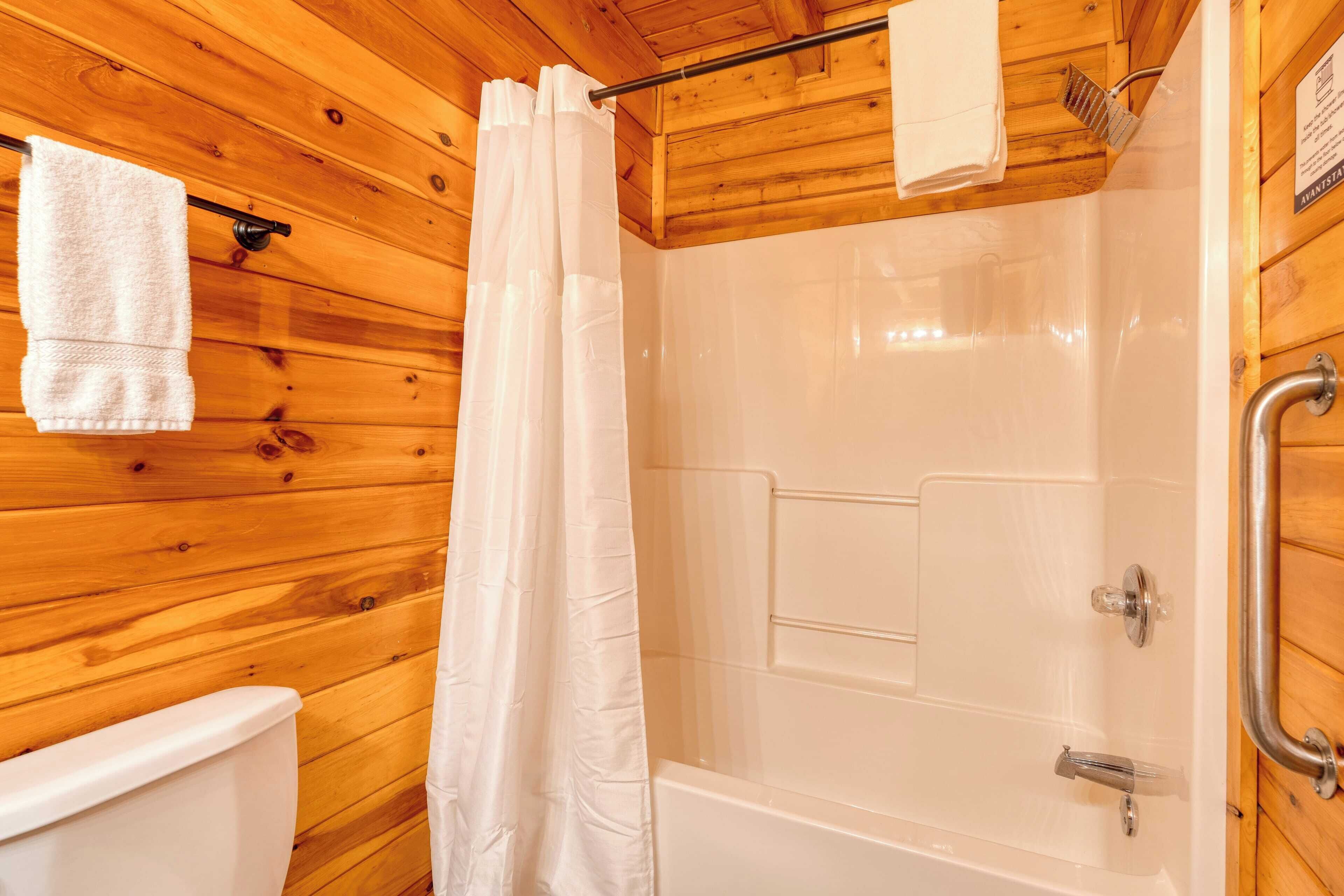 A wooden-paneled bathroom with a white bathtub, a shower curtain, and a towel rack.
