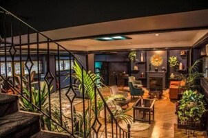 Um interior moderno com escada, área de estar e plantas decorativas.