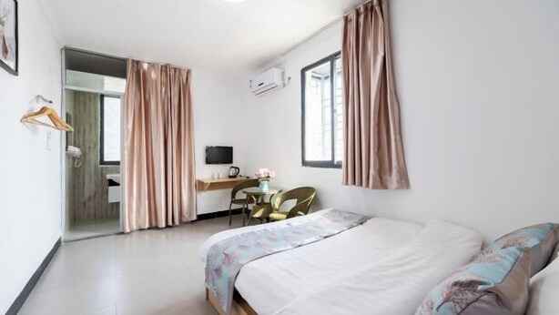 A hotel room with a bed, a desk, a chair, and a television. - Yijia Apartment (Xiamen Airport) (Xiamen)