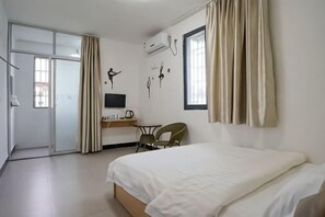 A hotel room with a bed, desk, chair, TV, and curtains. - Yijia Apartment (Xiamen Airport) (Xiamen)