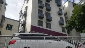 A multi-story building with balconies and a white car parked in front. - Yijia Apartment (Xiamen Airport) (Xiamen)