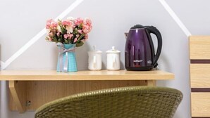 A wooden shelf with a vase of flowers, a white container, and a purple kettle. - Yijia Apartment (Xiamen Airport) (Xiamen)