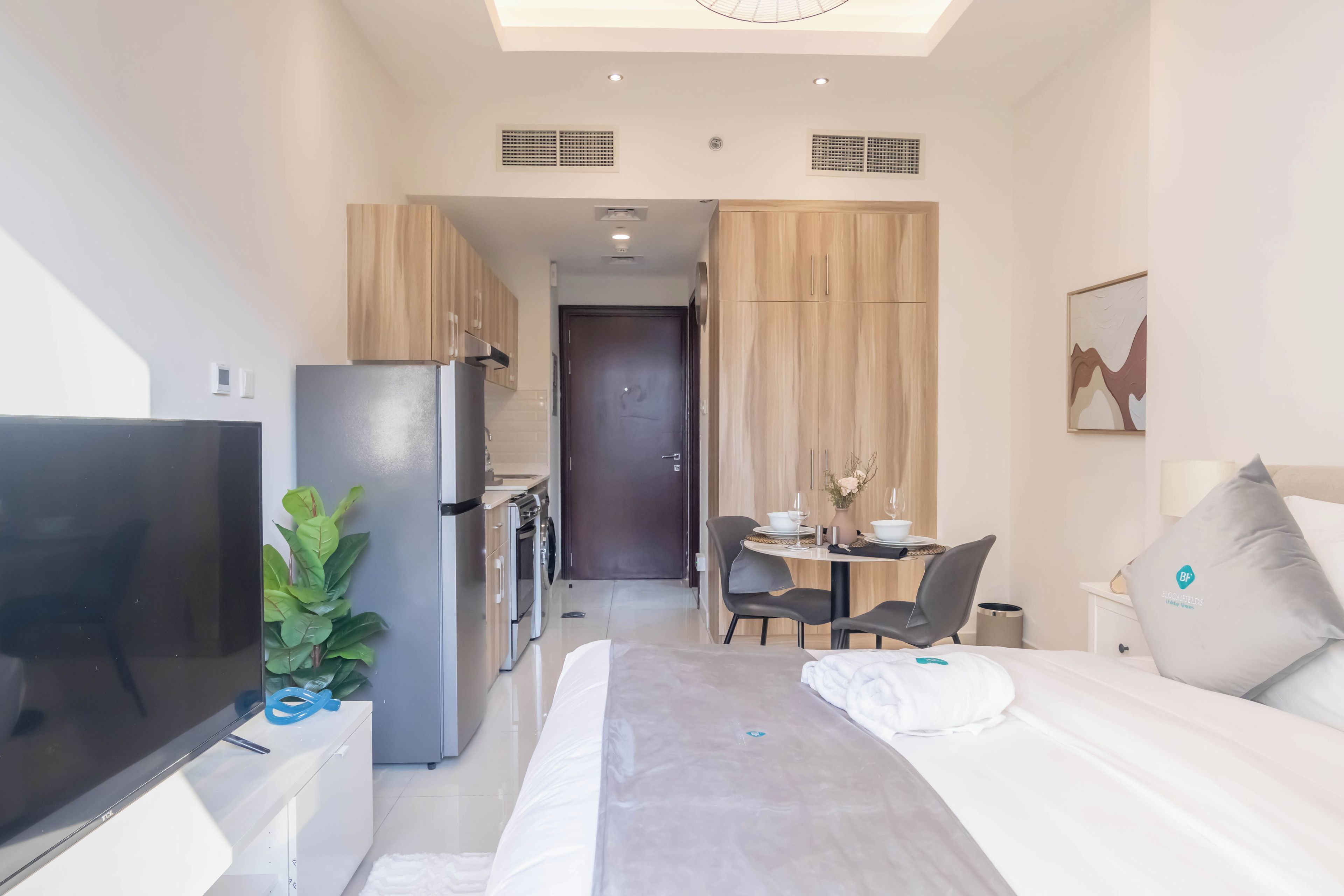 Habitación de hotel compacta con cama, televisión, kitchenette y zona de comedor.