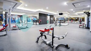 Uma academia moderna com diversos equipamentos de exercício, incluindo um banco de supino, uma estrutura para agachamento e uma máquina de polia.