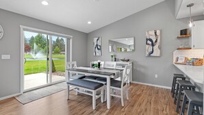 Eine moderne Küche mit Essbereich, großen Fenstern und Blick auf einen Garten.