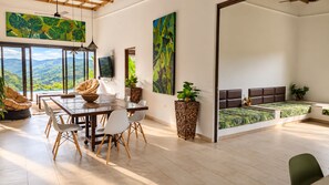 Una habitación amplia con comedor, un ventanal con vistas y una zona de estar con sofá y cama.