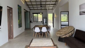 Et moderne interiør med et spisebord, en sofa og et køkken, der kan ses gennem en åben dør.