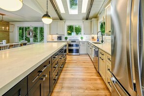 A modern kitchen with a central island, stainless steel appliances, and a view of greenery outside. - Lakefront Lake Anna Views, Dock, Beach (Bumpass)