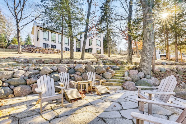 Une terrasse en pierre avec des fauteuils Adirondack et un muret en pierre.