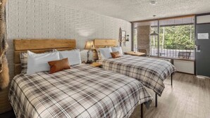 A room with two beds, a brick wall, a window with blinds, and a view of the outdoors. - 2 Queen Beds  Fast WiFi 50" TV  Salt Water Pool (Eureka Springs)