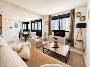 A modern living room with a sofa, coffee table, and a TV displaying 'NETFLIX'.