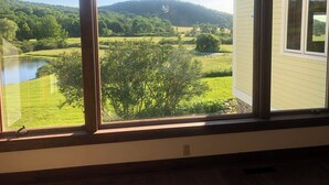 Une pièce dotée d’une grande fenêtre donnant sur un paysage verdoyant, avec des arbres et une étendue d’eau.
