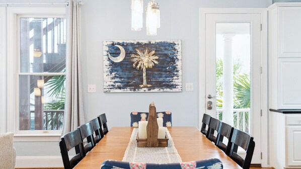 A dining room with a wooden table, black chairs, a decorative centerpiece, and a wall-mounted painting.