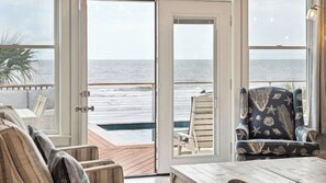 A room with a view of the ocean, a wooden deck, and a patterned armchair. - Oceanfront w/ Pool, Panoramic Deck Views, 5bdr Folly Ocean Breeze by Avantstay (Folly Beach)