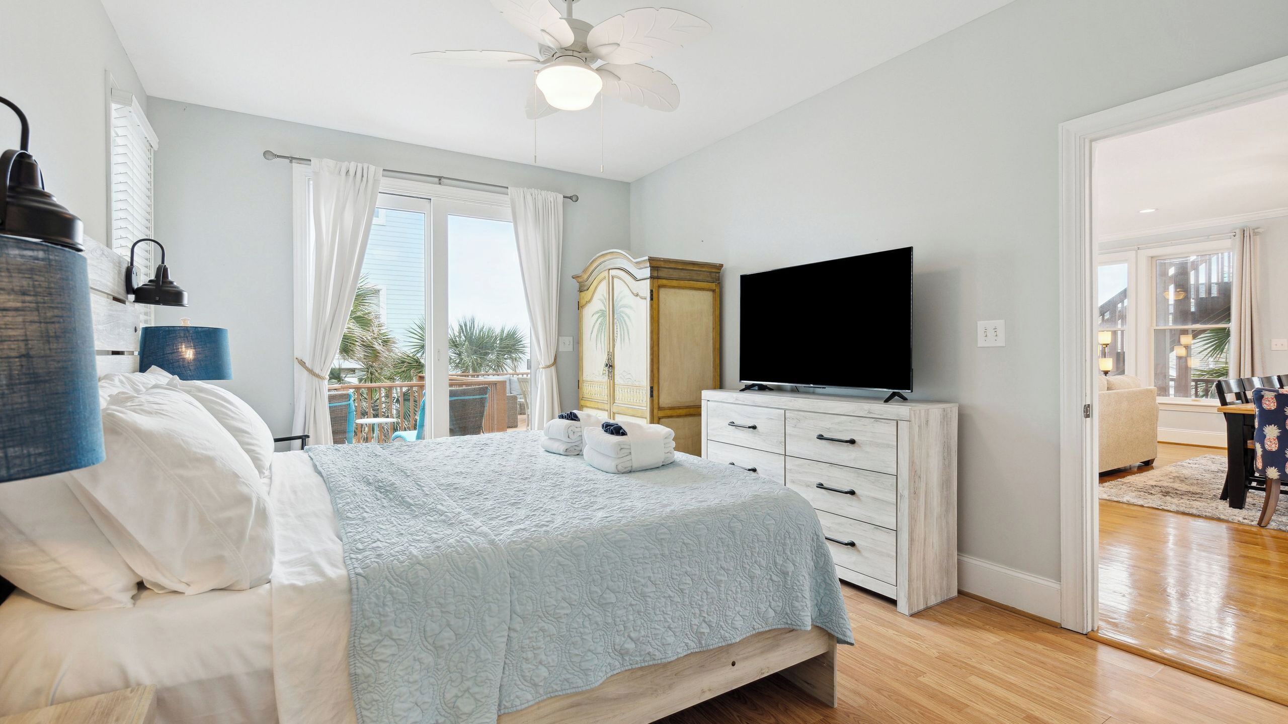 Un dormitorio con cama, televisor, armario y balcón con vistas.