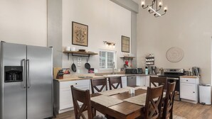 A modern kitchen with a stainless steel refrigerator, a microwave, and a coffee machine. There is a wooden dining table with four chairs and a rug on the floor. - Pond Property with Mountain Views (Bayfield)