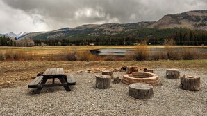 A picnic area with a wooden table and benches, surrounded by a gravel ground, with a lake and mountains in the background. - Pond Property with Mountain Views (Bayfield)
