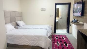 A hotel room with two beds, a TV, a phone, and a bathroom visible through an open door.