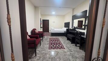 A hotel room with a bed, a desk, a chair, a sofa, and a mirror.