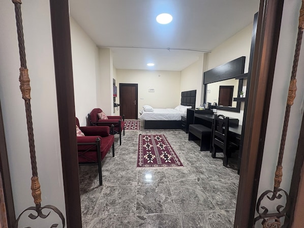 Una habitación de hotel con cama, escritorio, silla, sofá y espejo.
