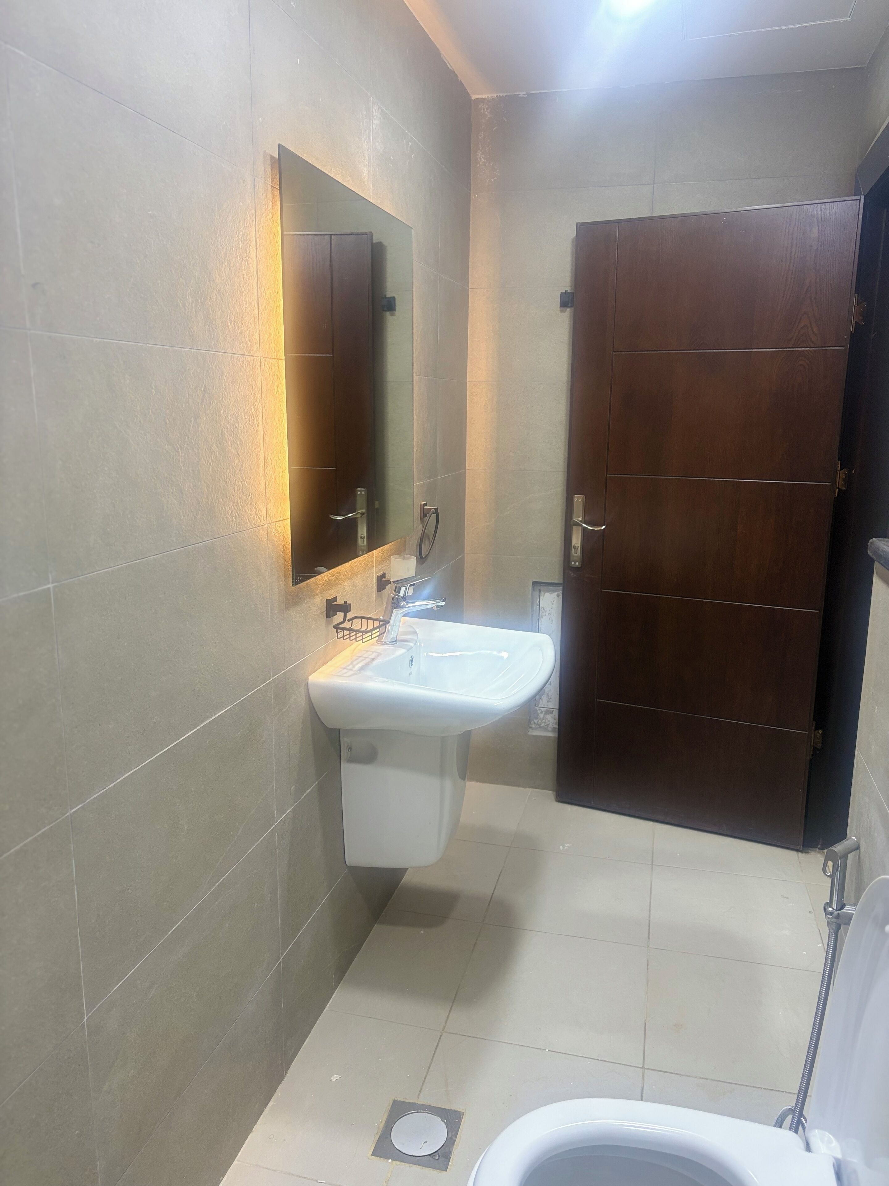 A bathroom with a white sink, a mirror, and a wooden door.