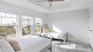 A bedroom with two beds, large windows, and a ceiling fan. - Modern 5bdr w/ Private Pool, 2 min Walk to the Beach! Montoute by Avantstay (Panama City Beach)