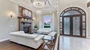 A spacious living room with a stone fireplace, white sofas, and a glass coffee table. - YVR/Luxe/Theatre/AC/New Westminster (New Westminster)