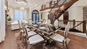 A spacious dining area with a high ceiling, elegant chandelier, and a grand staircase leading to an upper level. - YVR/Luxe/Theatre/AC/New Westminster (New Westminster)