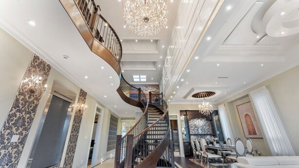 A spacious living area with a grand staircase, elegant chandeliers, and a modern kitchen. - YVR/Luxe/Theatre/AC/New Westminster (New Westminster)