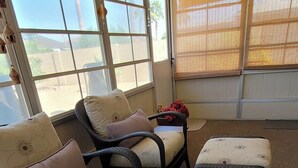 A room with a large window, wicker furniture, and a carpeted floor. - CASA Allegro - Active Vacationers Paradise (Sun City West)