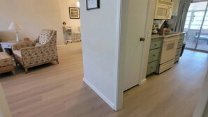 A spacious living area with a patterned armchair, a dining table, and a kitchen with a microwave and cabinets. - CASA Allegro - Active Vacationers Paradise (Sun City West)