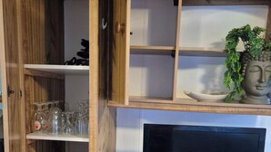 A wooden entertainment unit with a flat-screen TV, a remote control, and a small plant. - Mobile home N°17 (Fourmies)