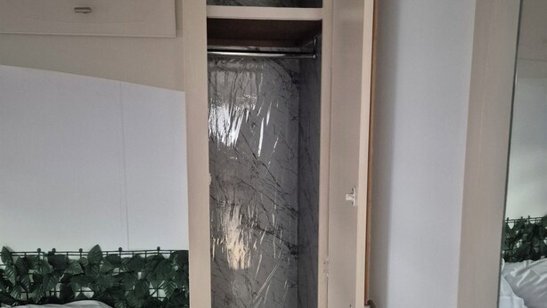 A bedroom with a bed, a wardrobe, and a marble wall. - Mobile home N°17 (Fourmies)