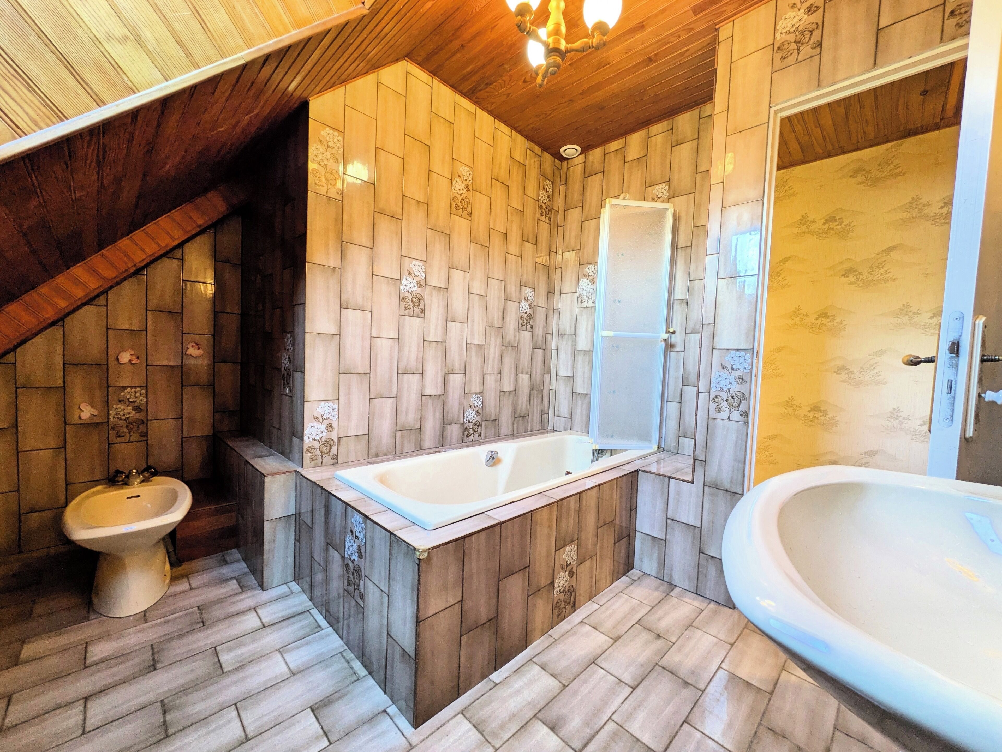 A bathroom with a wooden ceiling, a freestanding bathtub, a shower enclosure, and a toilet.