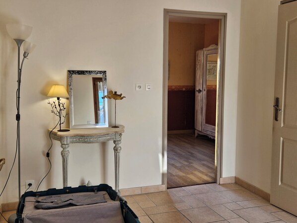 A room with a bed, a bedside table with a lamp, a mirror, and a wardrobe.