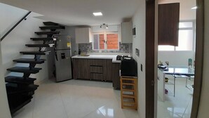 Una cucina moderna con una scala a scomparsa, un frigorifero e un piccolo angolo ristoro con tavolo e sedie.