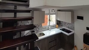 Una cucina moderna con isola centrale, mobili a scomparsa e un'ampia finestra che permette l'illuminazione naturale.