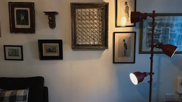 A room with a dark-colored sofa, a patterned wall hanging, and a floor lamp.