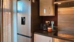 A modern kitchen with a stainless steel refrigerator, a built-in oven, and a microwave. - Villa Noria (Kingston Bagpuize)