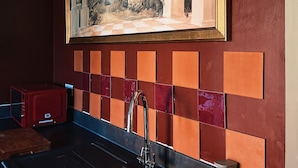 A kitchen with a large painting of a classical building, a tiled backsplash, and a modern faucet. - Villa Noria (Kingston Bagpuize)