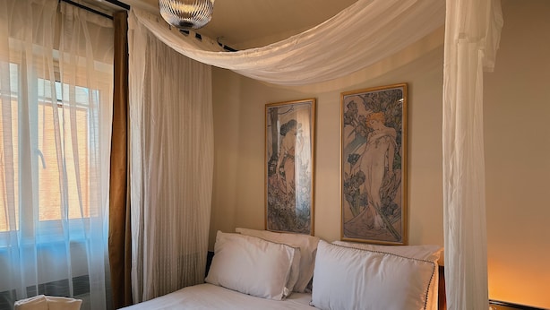 A neatly made bed with white linens, a basket of towels, and two framed artworks on the wall. - Villa Noria (Kingston Bagpuize)