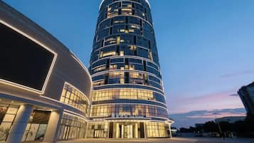 A modern hotel with a curved facade, multiple floors, and illuminated windows.