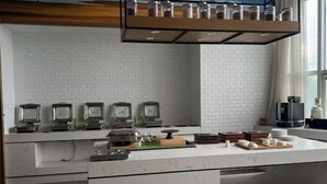 A modern kitchen with white subway tiles, a stainless steel range hood, and a countertop with various kitchen items.