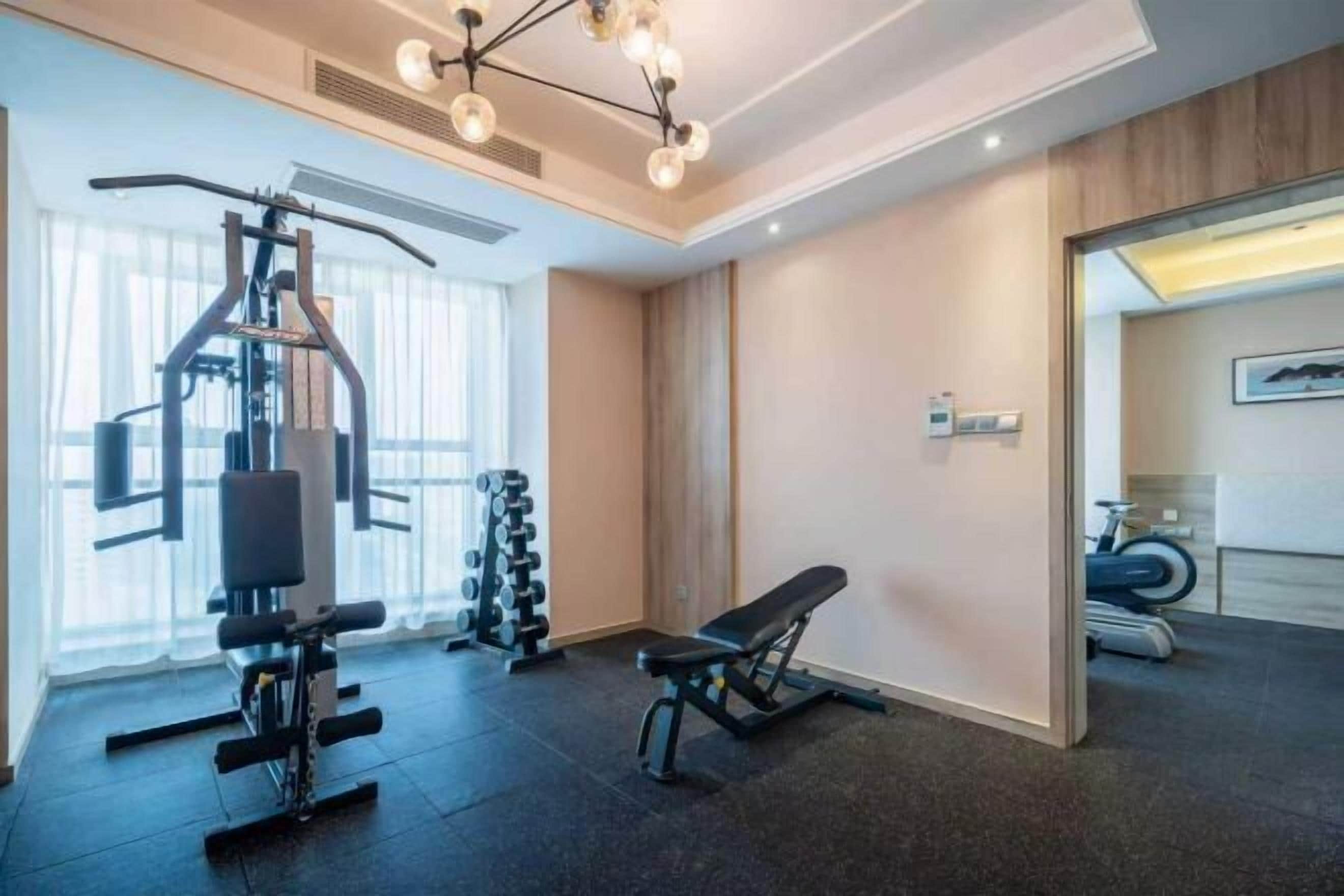A gym with exercise equipment, a bench, and a mirror.